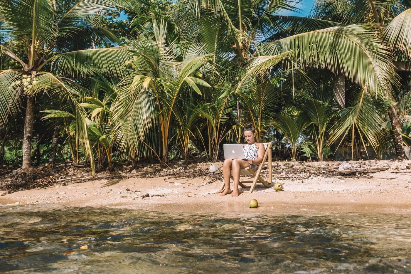 Remote worker using a laptop beside a tropical beach