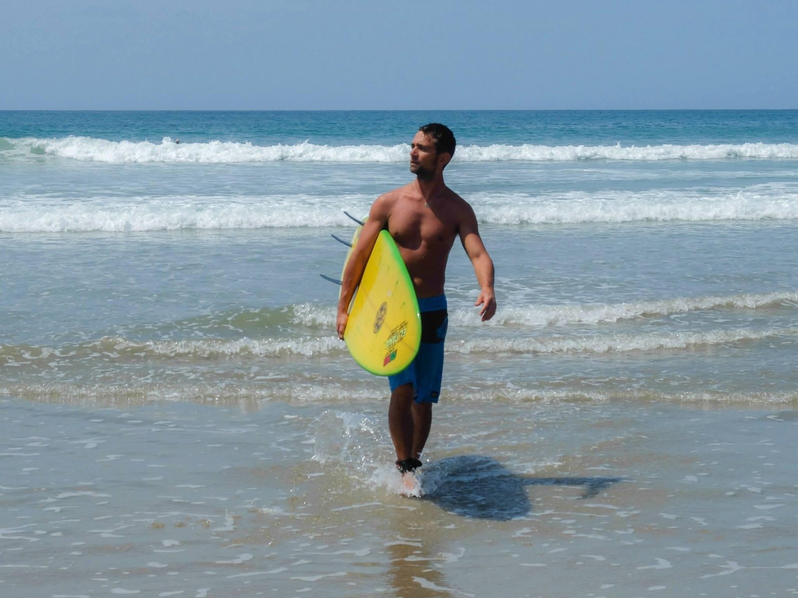 Surfer walking from the ocean with a yellow board